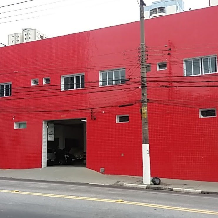 Fachada vermelha da oficina, com o portão de entrada aberto